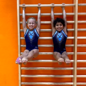 Zwei Mädchen mit Klappmessern/Kumpfbeuge an der Sprossenwand